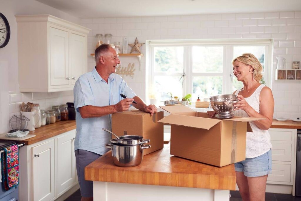two older adults packing kitchen items in boxes
