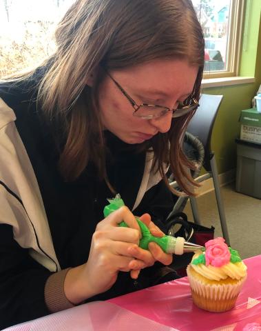 Teen decorating a cupcake