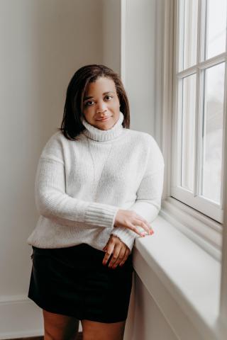 Charlene Thomas wearing white turtleneck sweater and black miniskirt