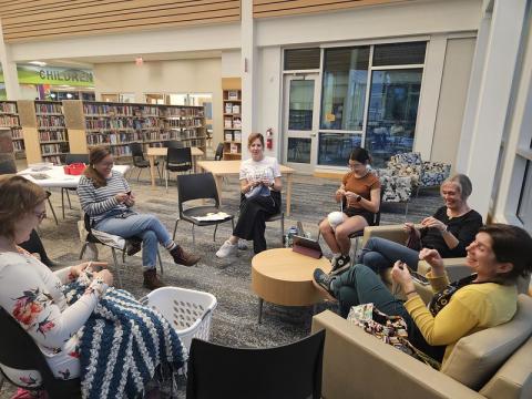 group of people sitting in the library knitting