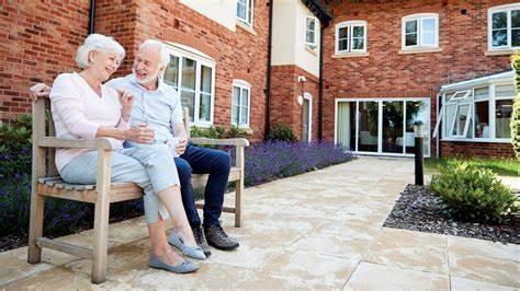 older adults sitting on bench in front of residence